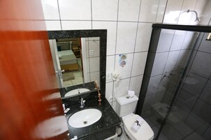 Un bagno con lavabo su piano nero, un water bianco e box doccia in vetro.