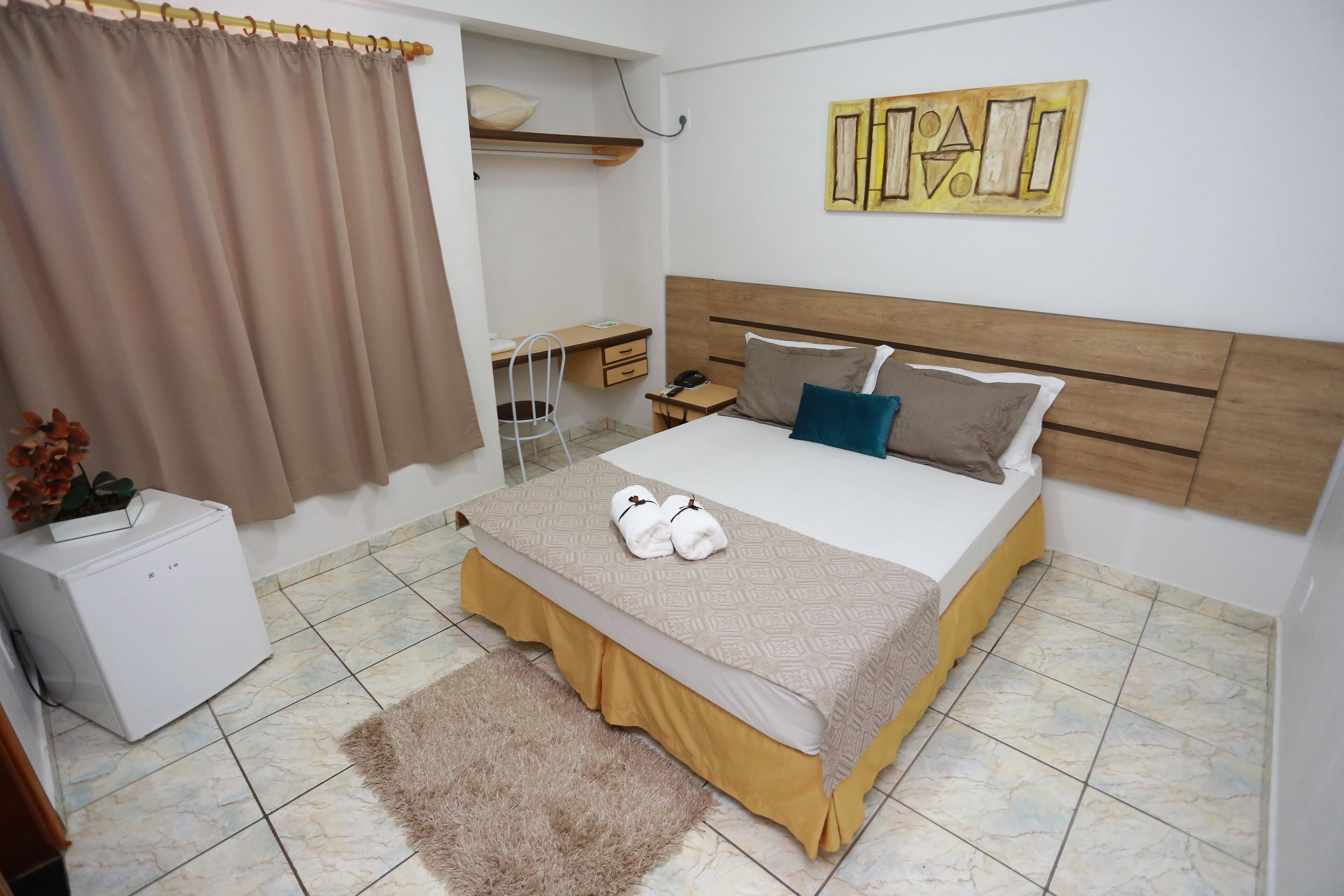 A bedroom with a bed, bedside table, and a small desk.