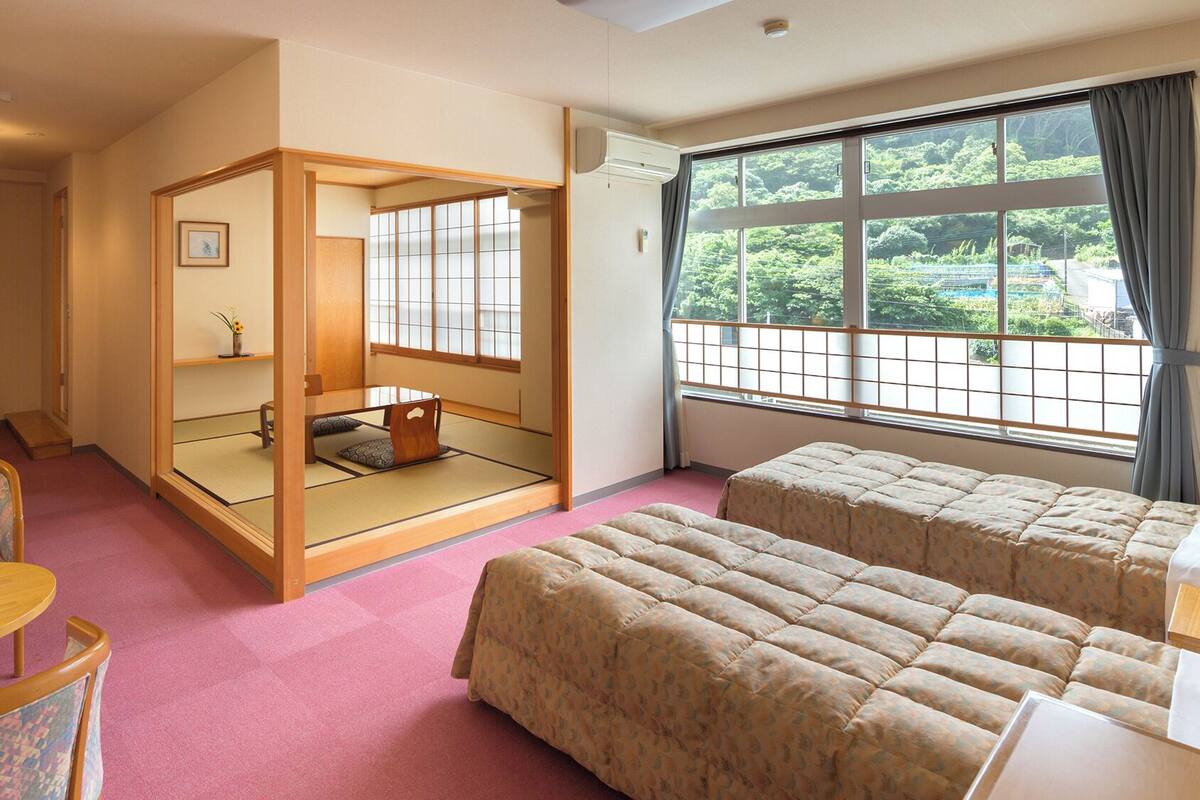 A traditional Japanese-style room with tatami flooring, a shoji screen, and futon beds.