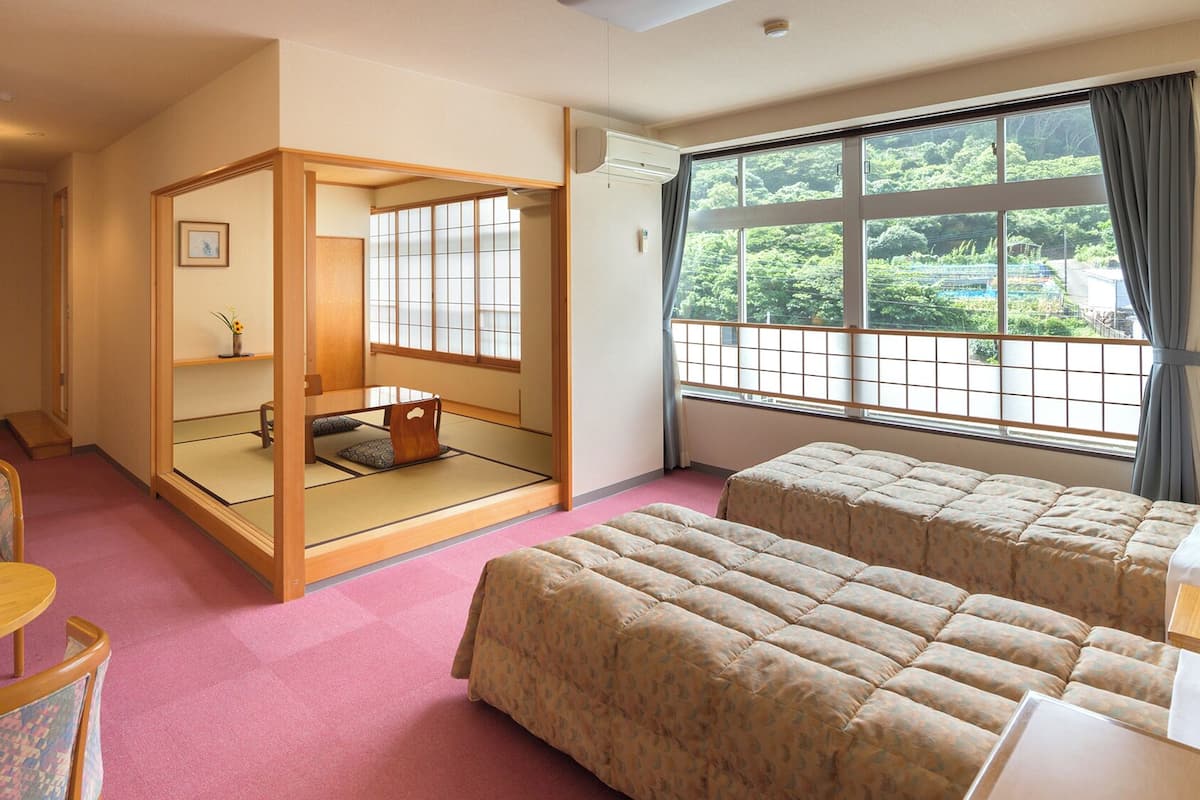 Una habitación tradicional japonesa con suelo de tatami, un biombó shoji y camas futón.