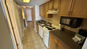 A kitchen with wooden cabinets, a stove, a microwave, and a dishwasher. - Ocean Villas Beach Resort (Myrtle Beach)