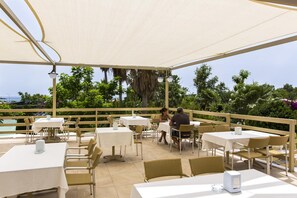 An outdoor dining area with tables and chairs, a pool in the background, and a view of the ocean. - Lycus Beach Hotel (Alanya)