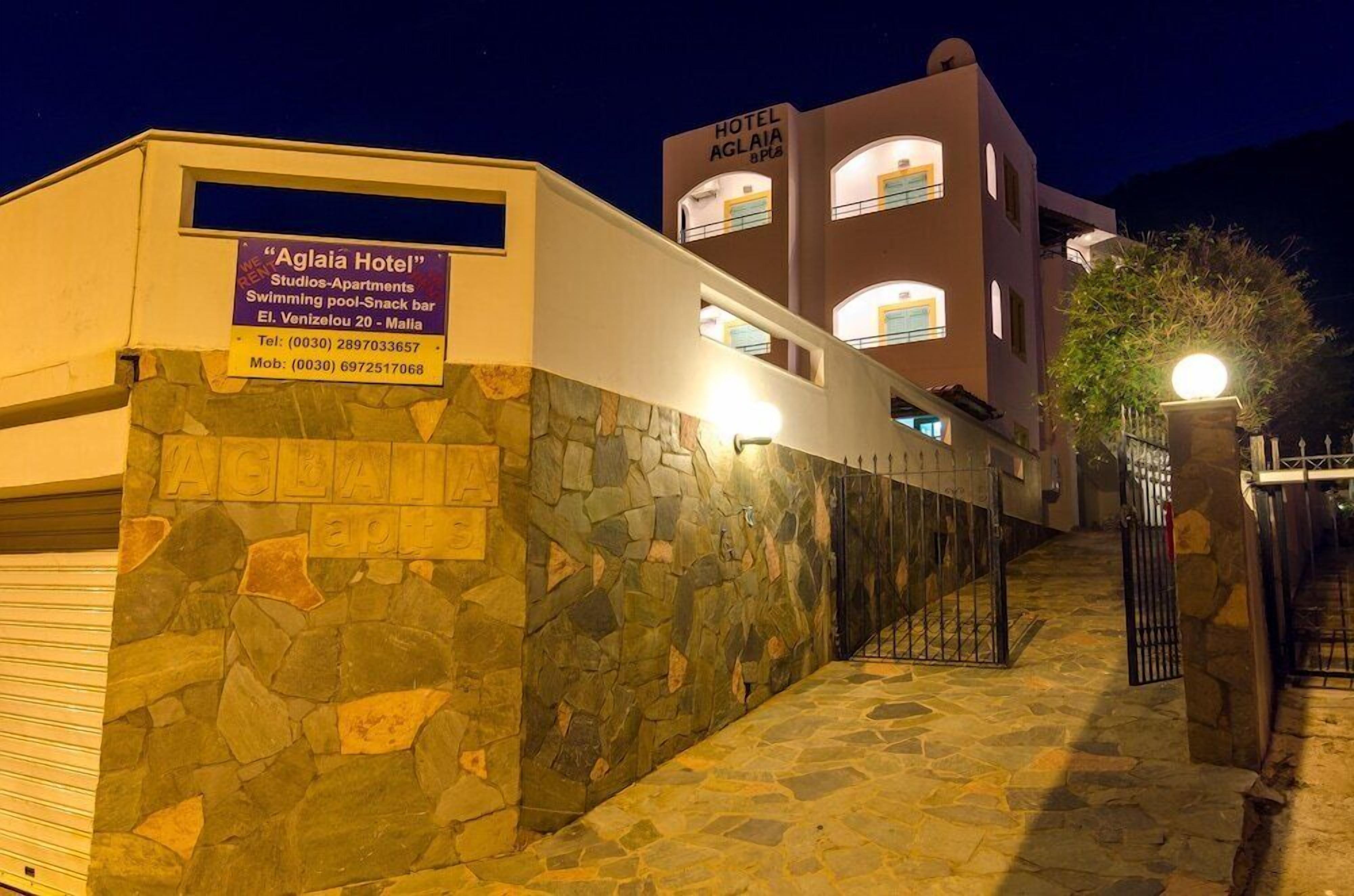 A stone-walled building with a sign for "Aglia Hotel" and "Hotel Aglia" in the background.