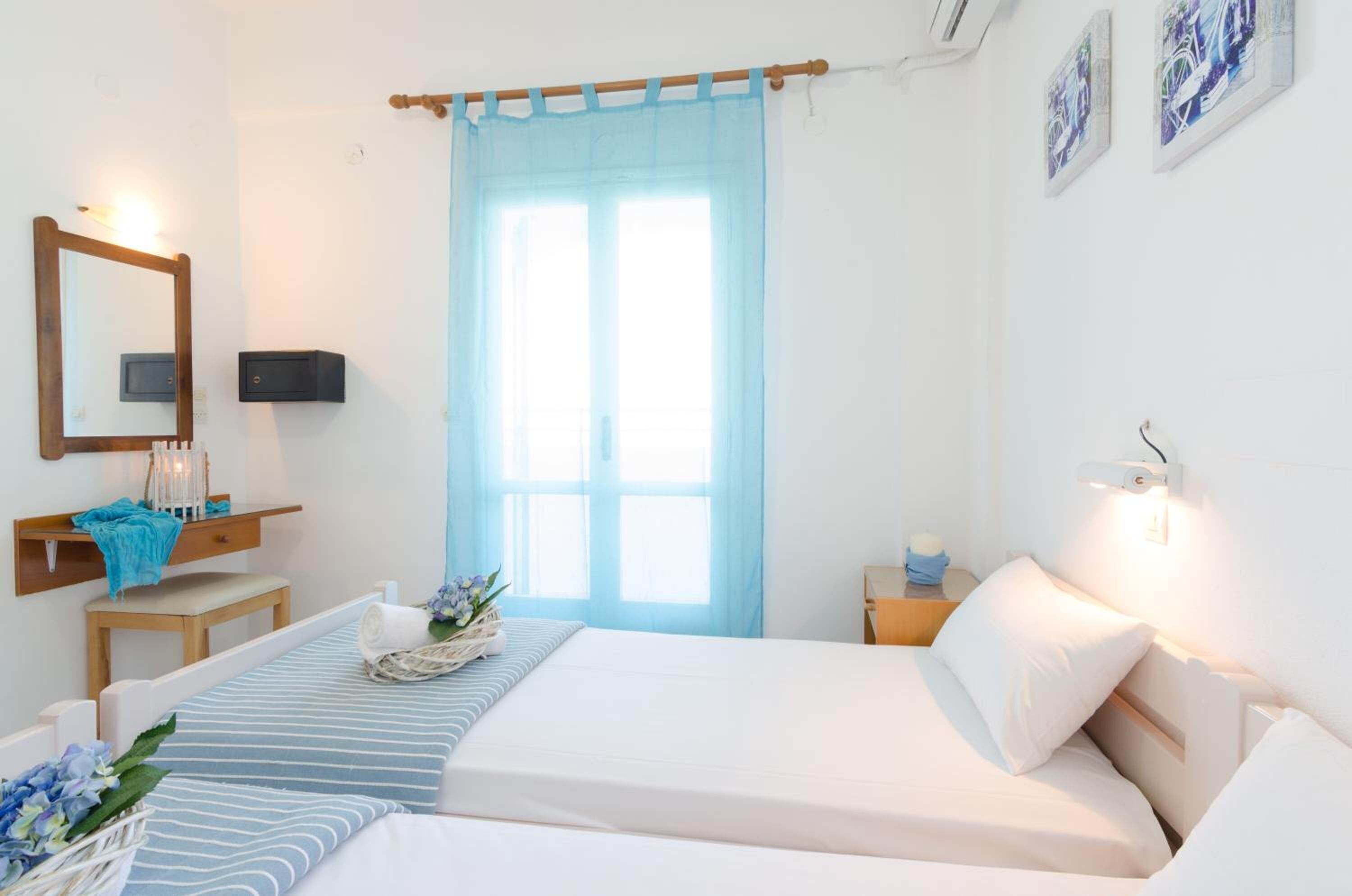 A bedroom with a bed, bedside table, lamp, and a window with curtains.