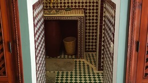 A narrow hallway with a checkered floor pattern, a sink area with a mirror, and a patterned wall. - Riad Zagouda (Marrakech)