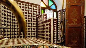 A bathroom with a checkered tile pattern, a decorative door, and a stained glass window. - Riad Zagouda (Marrakech)
