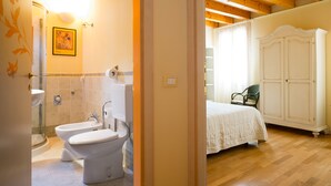 A bathroom with a toilet, bidet, and sink, and a bedroom with a bed and wardrobe. - Ca' Dei Fuseri (Venice)
