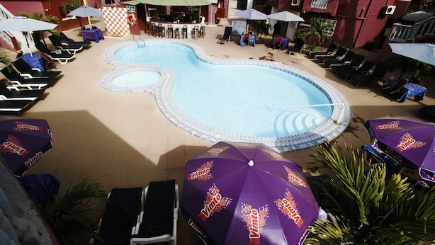 Una piscina con diseño de cuadros, rodeada de sillas de descanso y sombrillas.