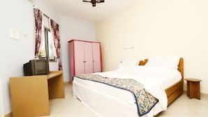 Un dormitorio con cama, televisor sobre un mueble bajo, armario y ventilador de techo.