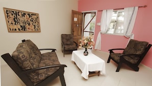 Un salón con sofás estampados, una mesita con un florero y una puerta que da al exterior.