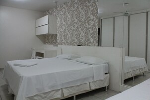 Quarto de hotel com cama grande, mesa de cabeceira, espelho e guarda-roupa.