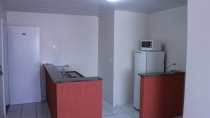 Eine kompakte Küche mit Kühlschrank, Mikrowelle, Spüle und einer Tür, auf der die Nummer 302 steht.