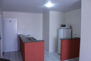 Cozinha compacta com geladeira, micro-ondas, pia e uma porta com o número 302.