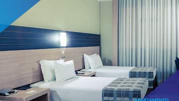 A hotel room with two beds, a nightstand, and a window with curtains. The room has a modern design with a blue accent wall and a wooden headboard.