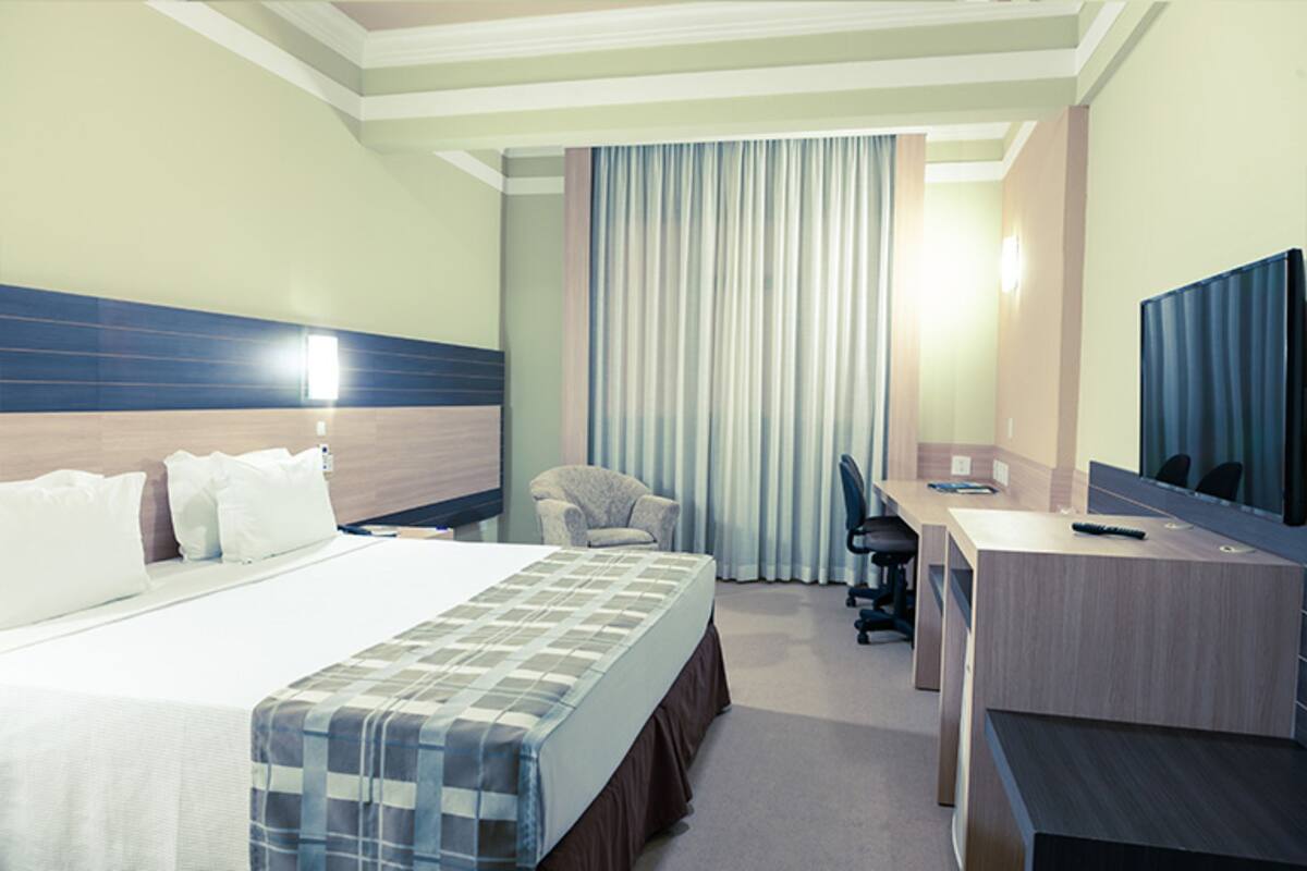 Una habitación de hotel con una cama grande, un escritorio, una silla y un televisor.