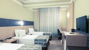 Una habitación de hotel con dos camas, un escritorio, una silla y un televisor.