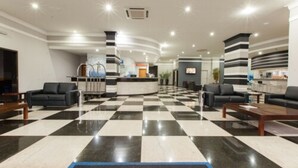 Un vestíbulo con piso a cuadros, pilares rayados en blanco y negro y un mostrador de recepción.