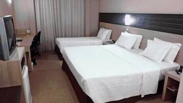 A hotel room with two single beds, a desk, and a television.