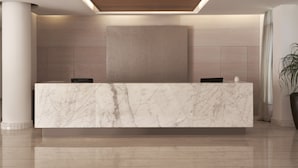 A reception desk with a marble top, wooden ceiling, and a large plant to the right. - Atlantica Holiday Village Rhodes (Rhodes)