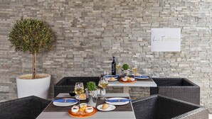 A dining area with stone walls, wicker furniture, and a sign reading "La Trattoria". - Atlantica Holiday Village Rhodes (Rhodes)