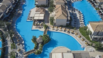 Un resort con una amplia piscina central, varias villas para huéspedes y zonas de estar al aire libre.