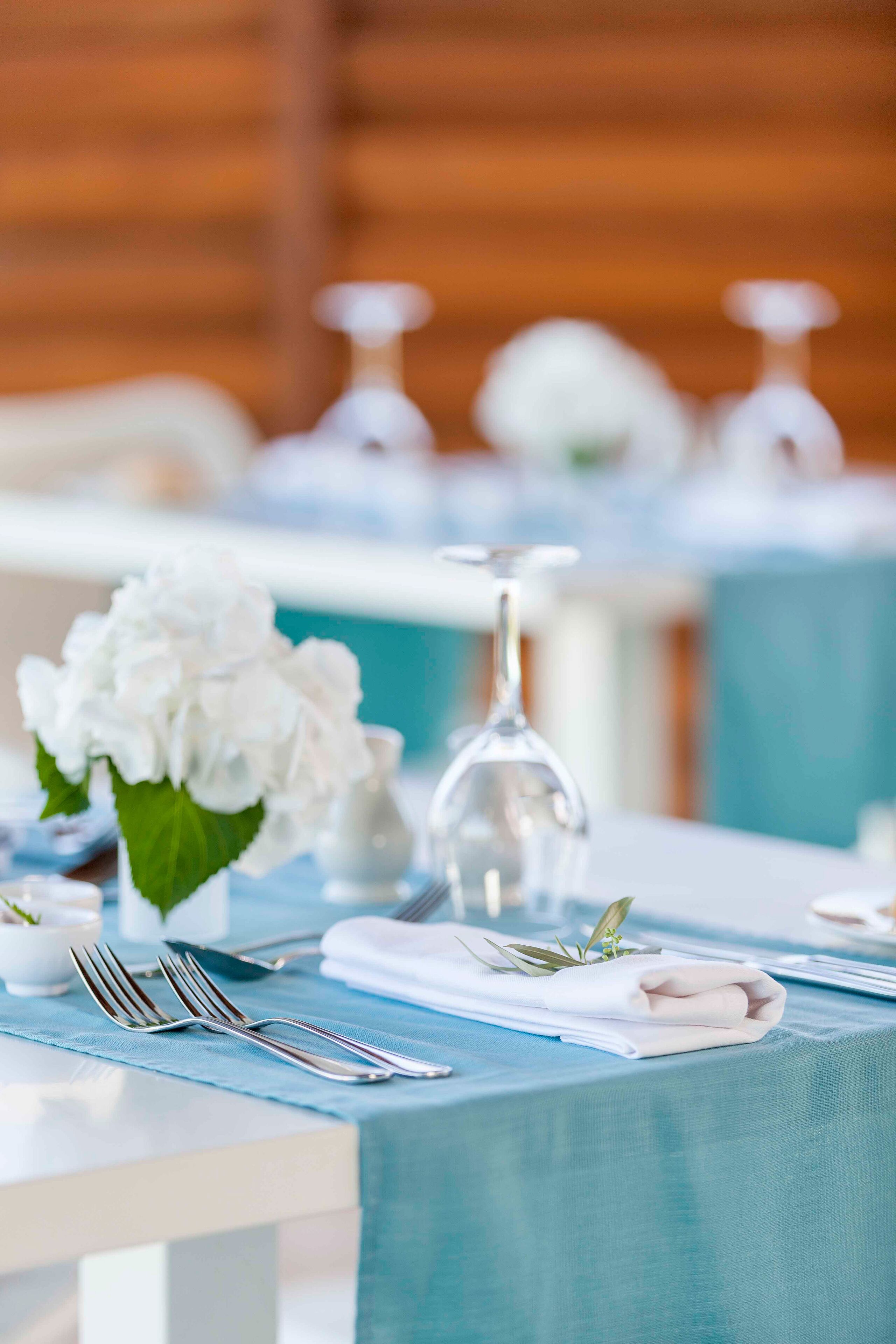 A table set with white flowers, clear glassware, and neatly folded napkins.