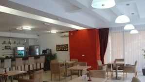 Un vestíbulo de hotel con varias zonas de estar, un mostrador de recepción y un bar.