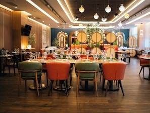 A restaurant interior with round tables, chairs, and overhead lighting. - Hotel Mepas (Mostar)