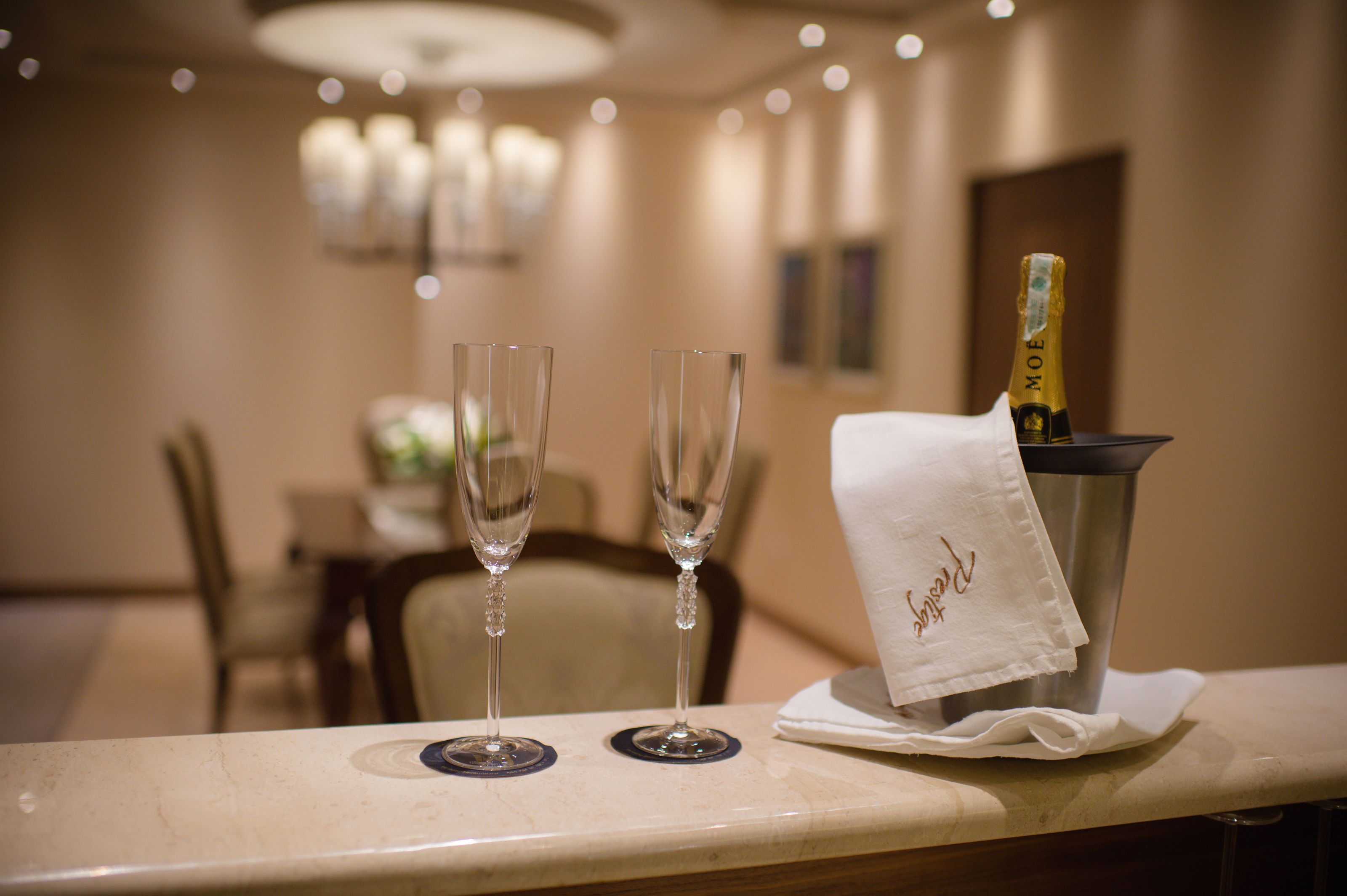 A table with two empty champagne flutes and a bottle of Moët champagne in a bucket, with a white napkin on top.