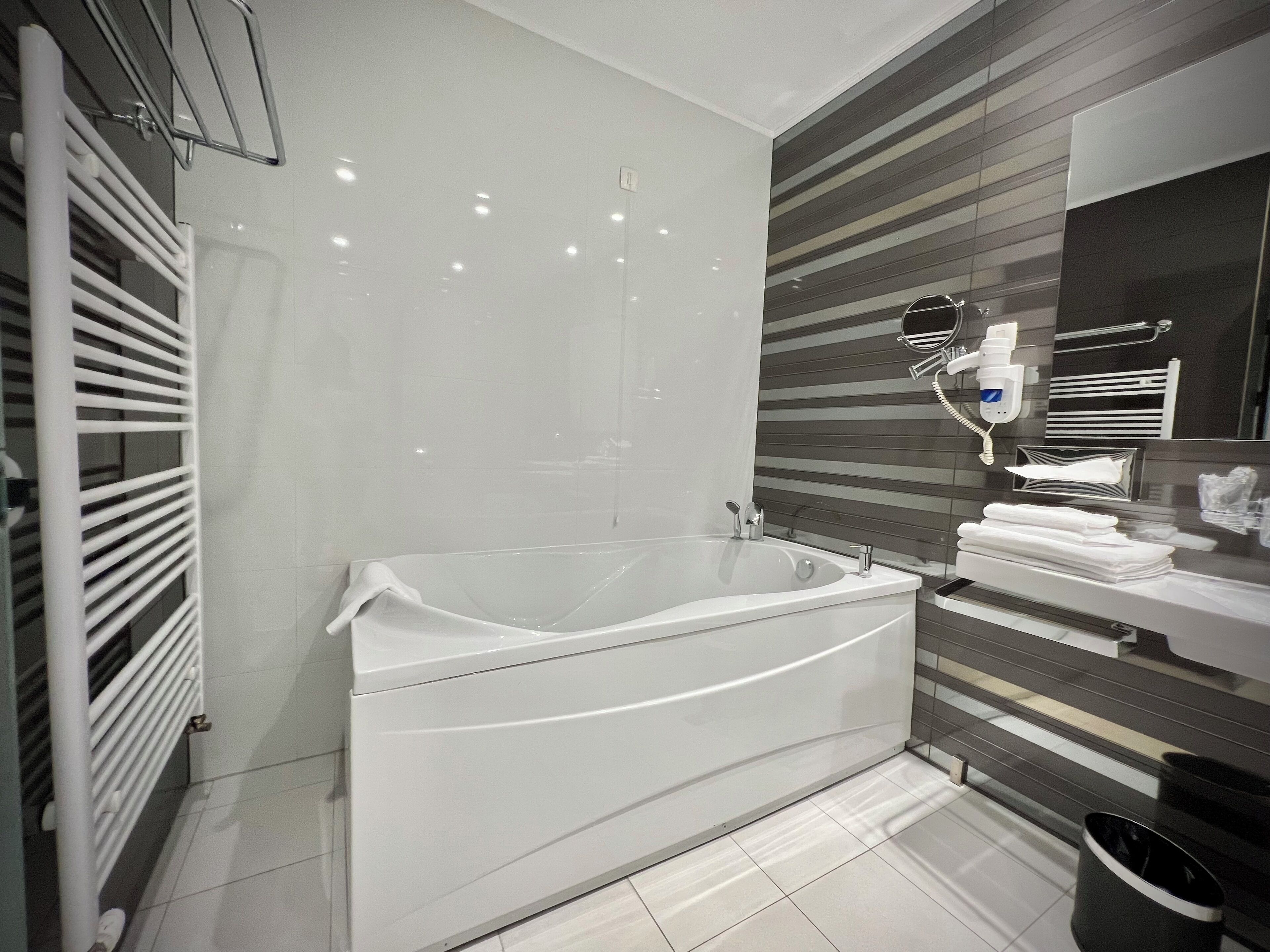 Un baño moderno con una bañera independiente, un perchero para toallas y un espejo.
