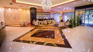 Un hall d’hôtel doté d’un grand lustre, d’un comptoir d’accueil et de plusieurs espaces aménagés avec des sièges.