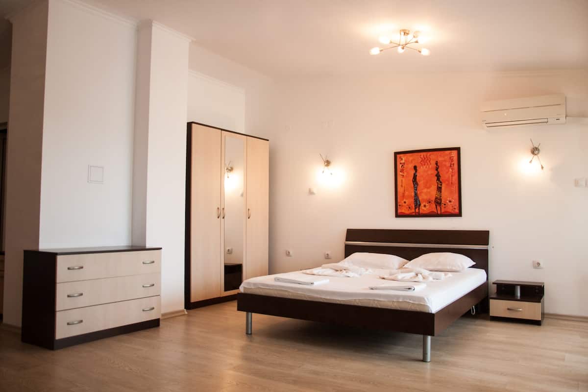 Un dormitorio con cama, armario, mesita de noche y aire acondicionado.