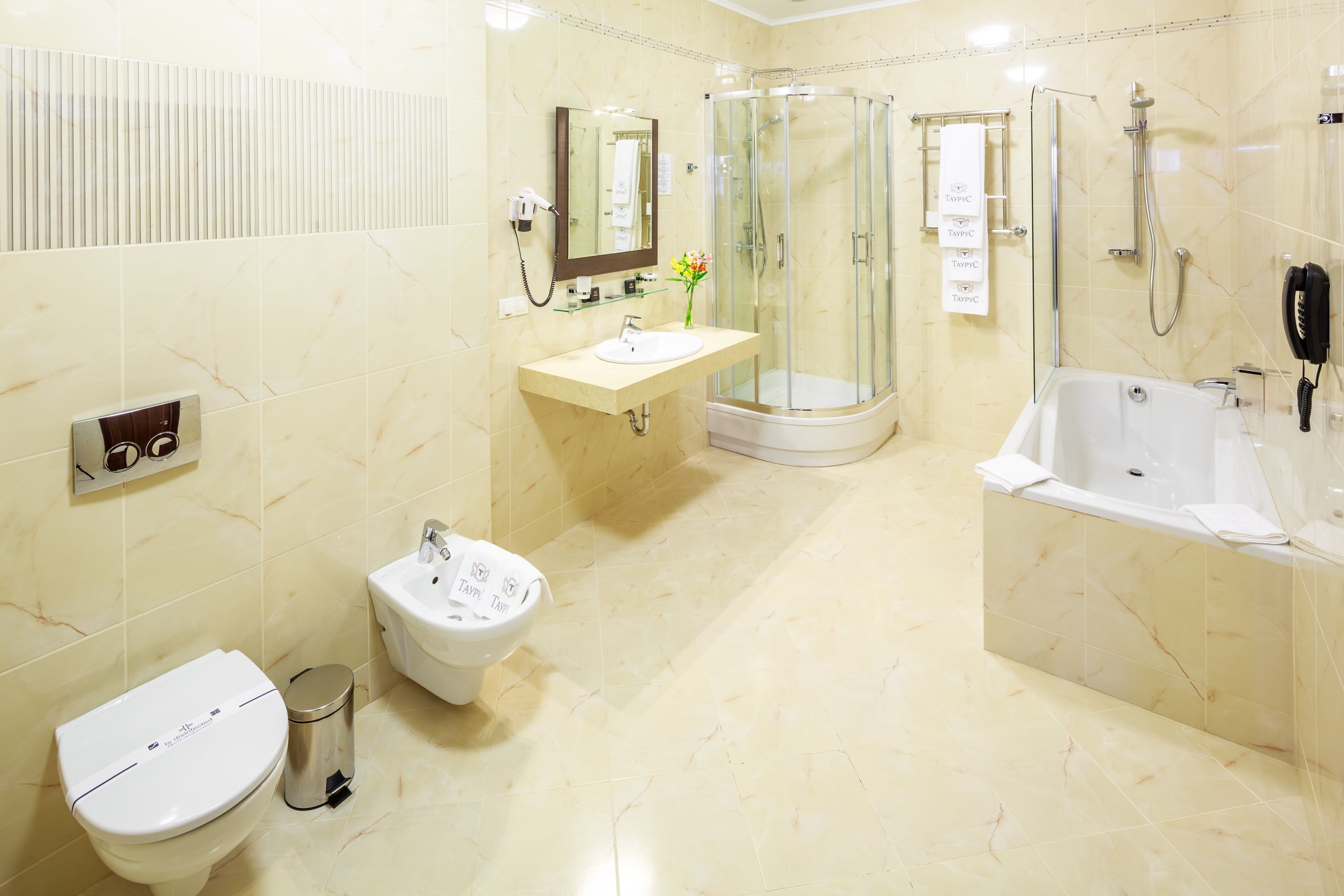 A modern bathroom with a toilet, bidet, sink, glass-enclosed shower, and bathtub.