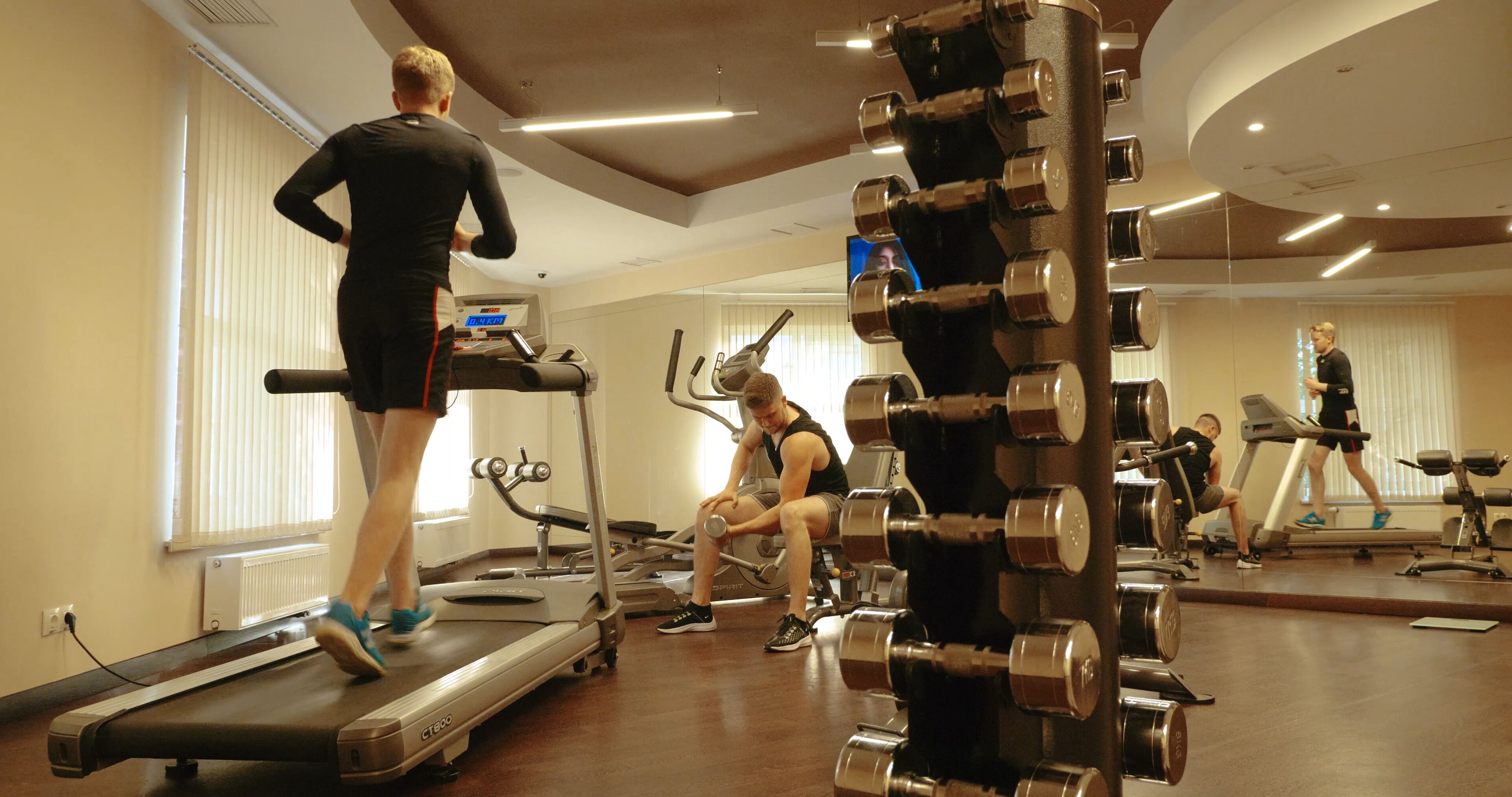 A gym with treadmills, weight machines, and dumbbells.