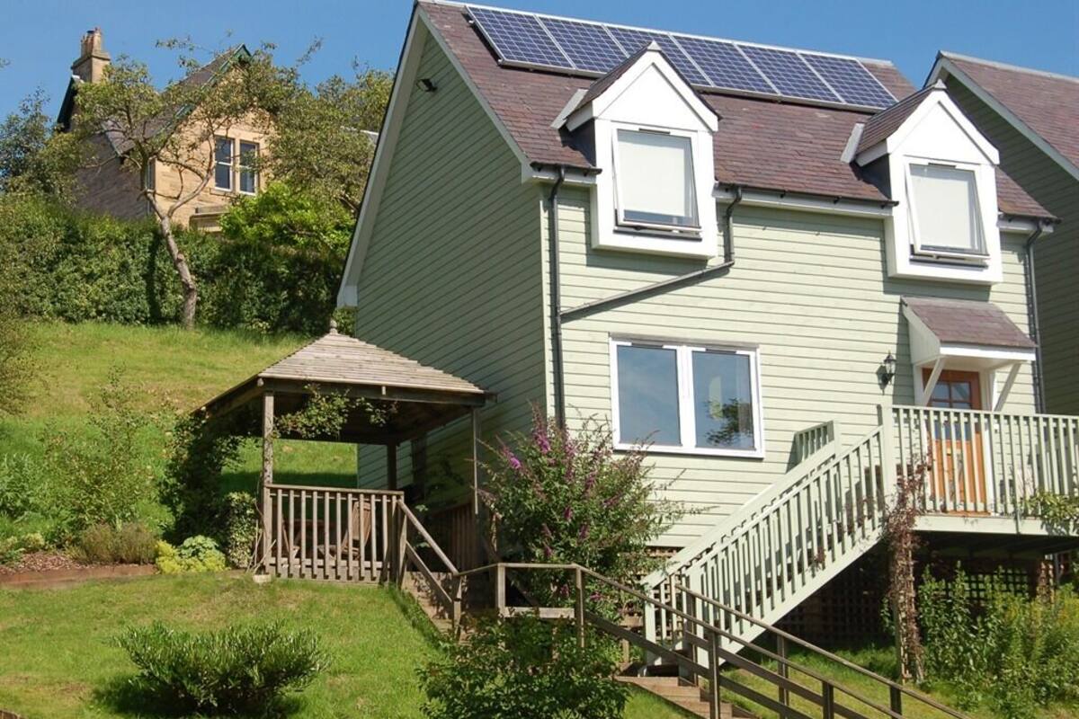 A two-story house with a covered porch, a staircase, and solar panels on the roof.