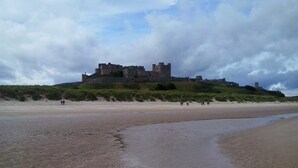 Un château perché sur une colline, dominant une plage.
