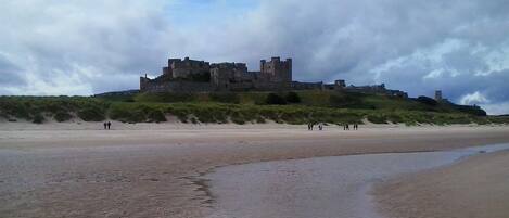 A castle on a hill overlooking a beach.