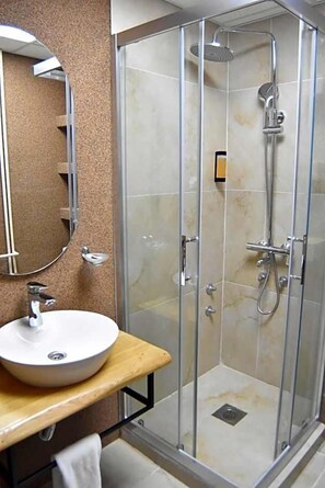 A bathroom with a glass-enclosed shower, a sink with a mirror, and a towel rack. - Montana Palas Hotel (Krusevo)