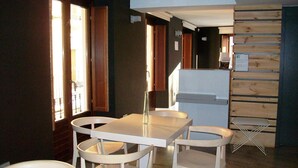 Een eetruimte met een witte tafel en stoelen, een houten kast en een raam met gordijnen.