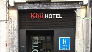 De ingang van Khü Hotel, met een zwarte gevel en een bord waarop staat dat het een hotel is.