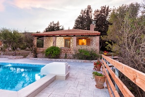 A stone house with a pool, wooden deck, and potted plants. - Liuba Houses (Zakynthos)