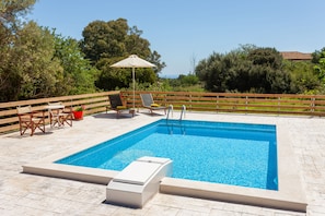 A rectangular swimming pool with a wooden deck, surrounded by a wooden fence. - Liuba Houses (Zakynthos)