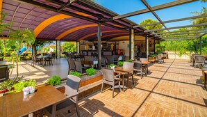 An outdoor patio area with tables and chairs, a covered seating area, and a view of the surrounding greenery. - Clover Magic Park Beach Alanya (Alanya)
