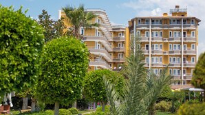 A multi-story residential building with balconies, surrounded by well-maintained greenery and a clear sky. - Clover Magic Park Beach Alanya (Alanya)