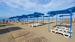 A beach with blue umbrellas and white lounge chairs. - Clover Magic Park Beach Alanya (Alanya)