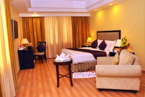 A hotel room with a bed, a sofa, a desk, and a chair. - Gokulam Park Sabari OMR Hotel (Tirupporur)