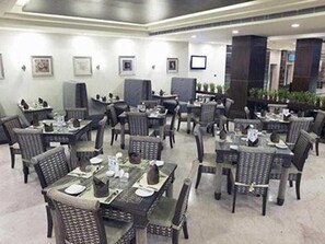 A restaurant with multiple tables and chairs, some with menus and glasses. - Gokulam Park Sabari OMR Hotel (Tirupporur)