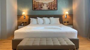 Una habitación de hotel con una cama grande, dos lámparas de noche, un cabecero y un cuadro en la pared.