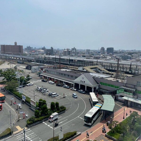 A train station with multiple tracks, a bus terminal, and a parking area with vehicles. - Terminal Hotel Matsuyama (Matsuyama)