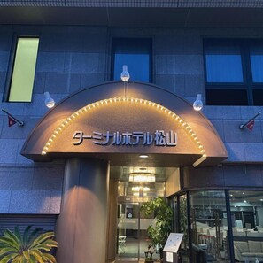 A hotel entrance with a curved awning and illuminated sign. - Terminal Hotel Matsuyama (Matsuyama)